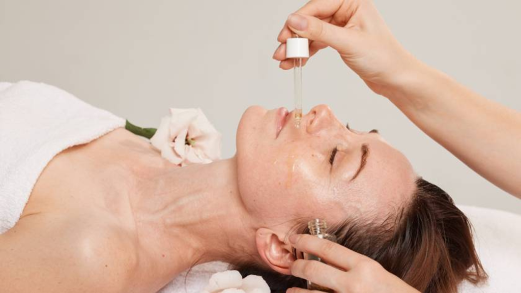 A woman having drops of vitamins for healthy skin applied to her face.