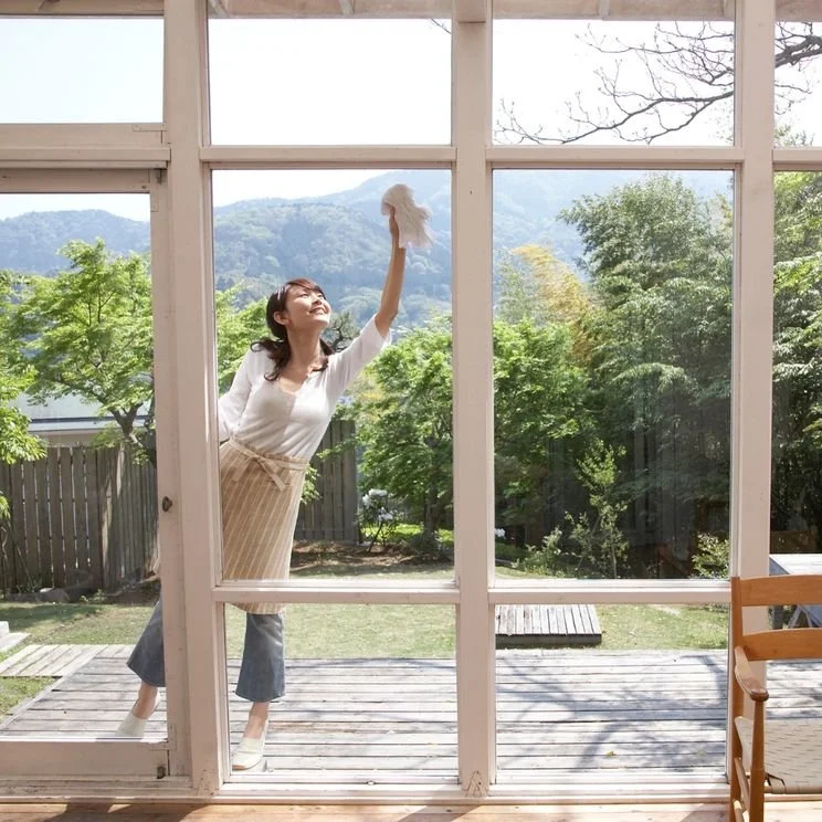 A woman cleaning windows with DERMAGLOVE. Clean living doesn't mean chemical avoidance.